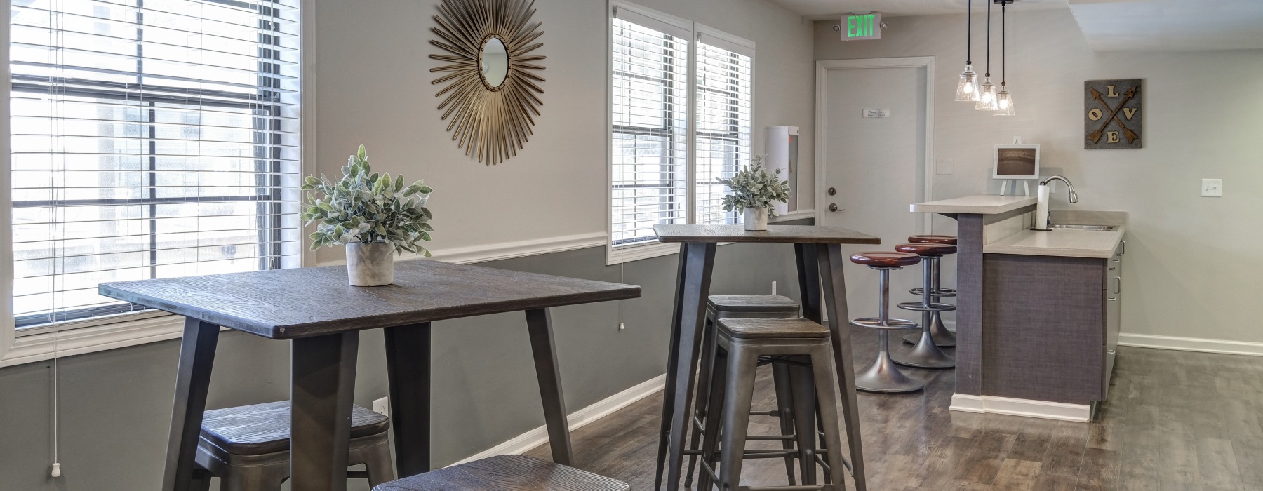 Room with bar top tables and a kitchen